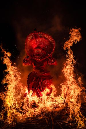 Man performing Theyyam ritual form of dance worship surrounded by fire