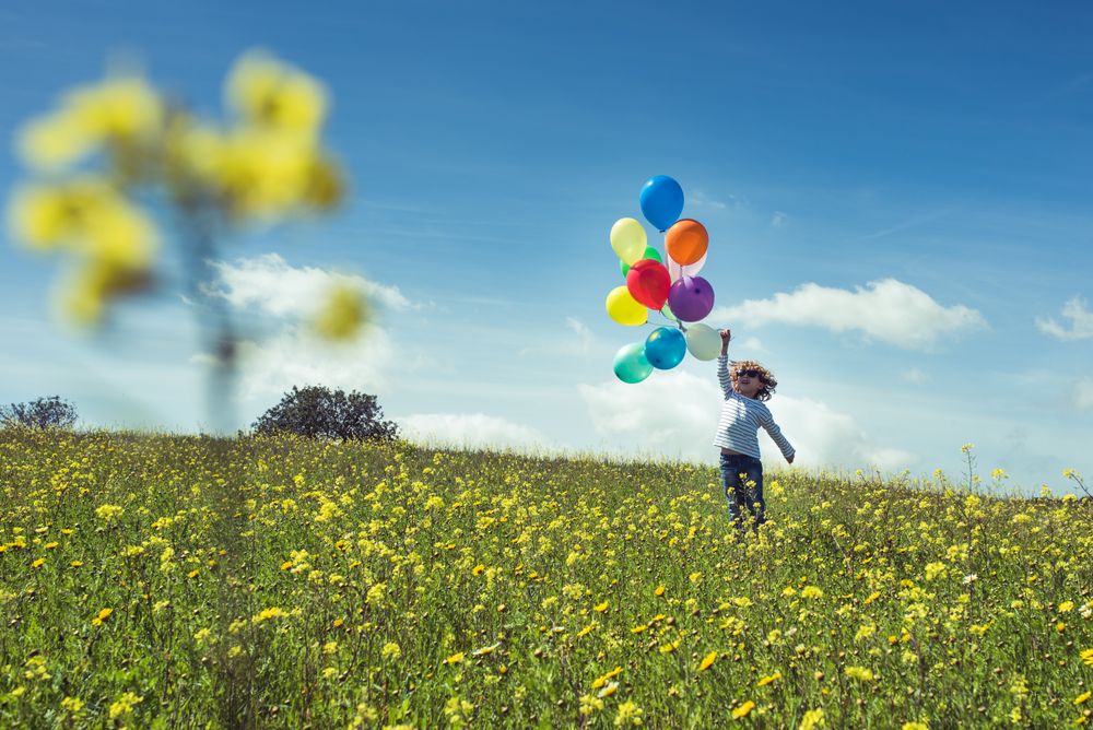 Kid having fun with balloons in nature