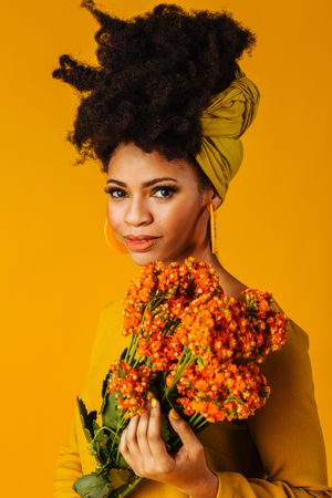 Portrait of serious Black woman holding orange flowers