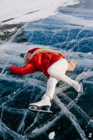 Happy woman in skates lying on ice
