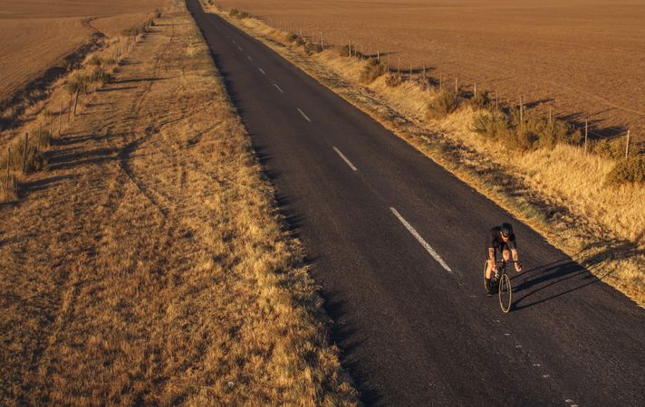 Athlete cycling on empty countryside road