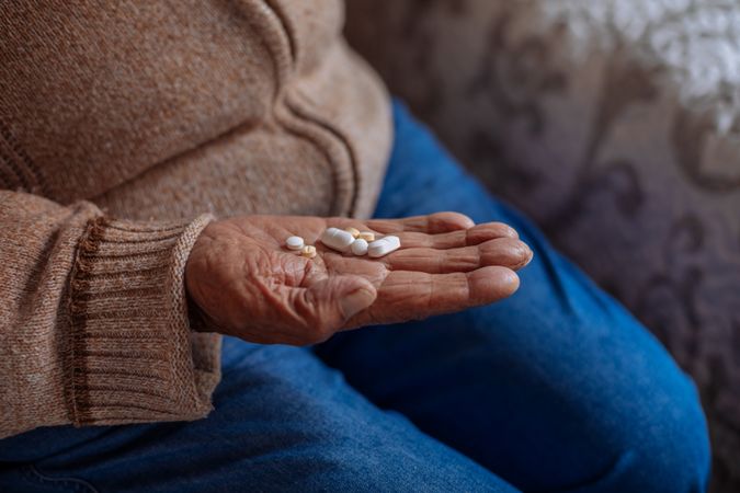 Detail of pills on the hand of an old man