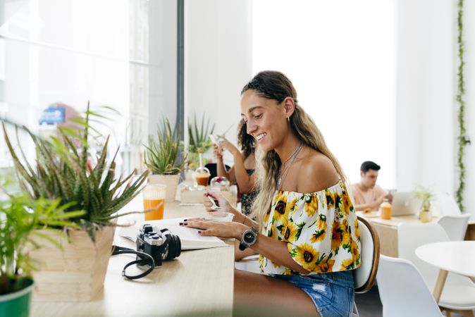 Stylish woman eating and reading book in cafe
