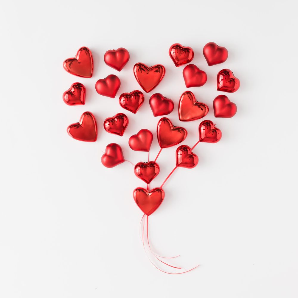 Heart made of red foil hearts on light background