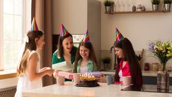 Family gathered around as girl opens gifts, smiling and excited.