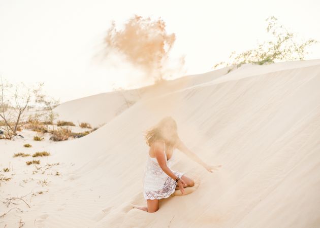 Woman having fun throwing sand in desert