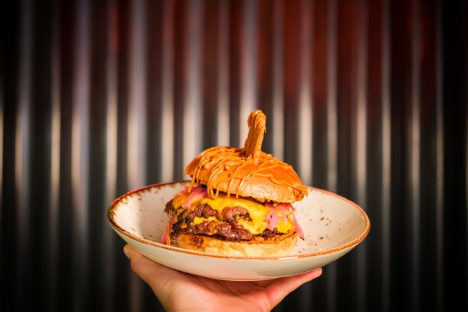 Unrecognizable person with hamburger on plate