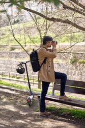 Male photographer stepping on bench and taking photo on camera