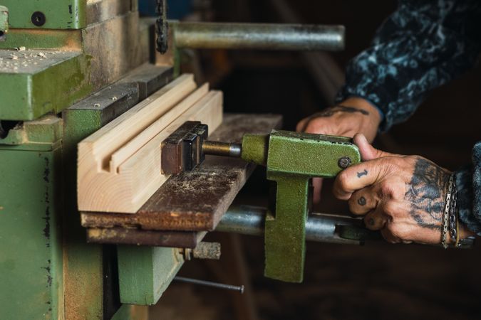Crop craftsman using wood drilling machine in workshop