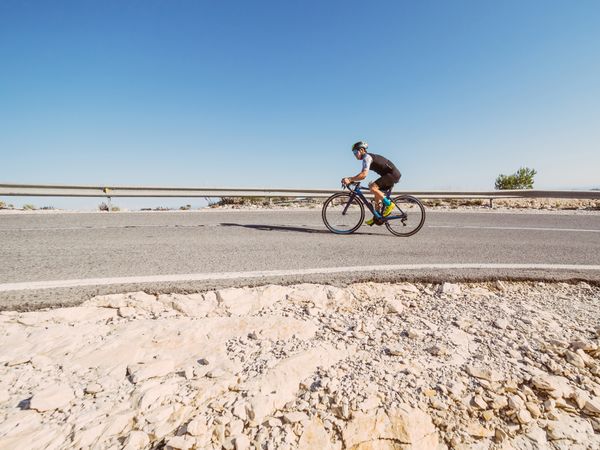 healthy man riding a bicycle on a mountain road in a sunny day