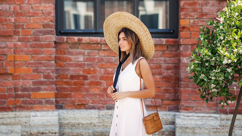 Woman walking next to brick building in summer time