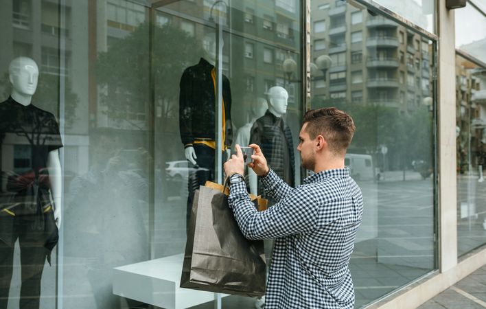 Man taking a photo of a shop window of a fashion store