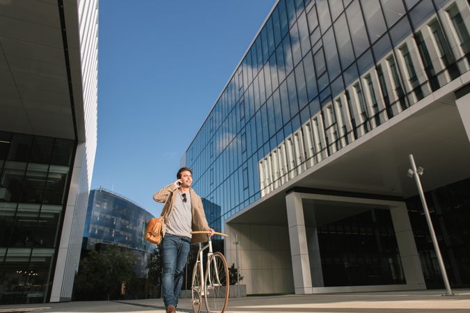 Man phoning while standing against modern building in downtown
