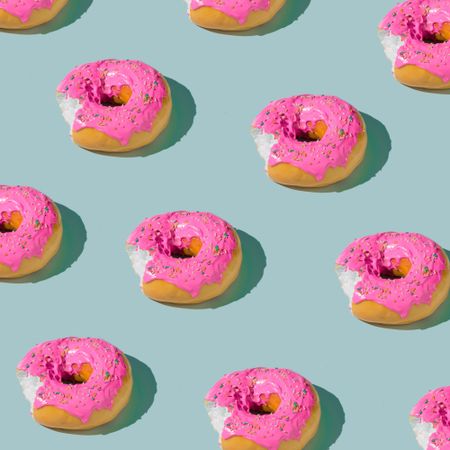 Patter of pink glazed donut on blue pastel background