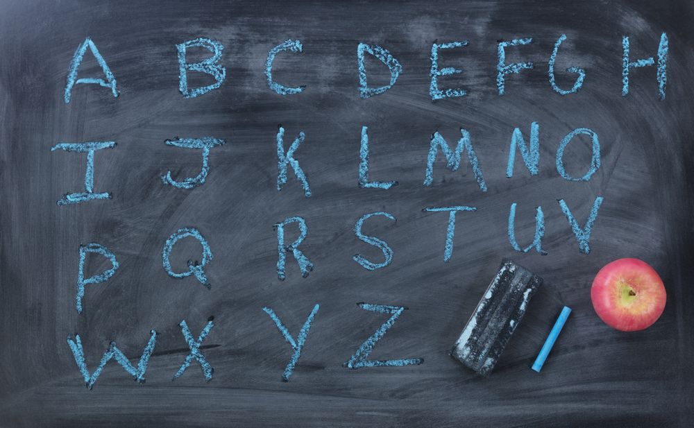 English alphabet letters written on chalk board with eraser and apple