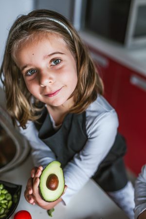 Little girl showing cut avocado
