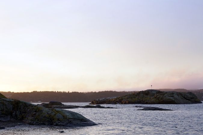 Rocky shore of tranquil sea in dusk