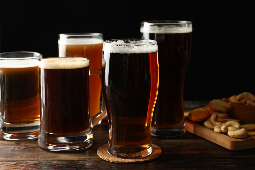Glasses of beer and snacks on wooden table