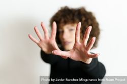 Blurred woman in dark sweater looking through two hands with palms to the camera 5n7684