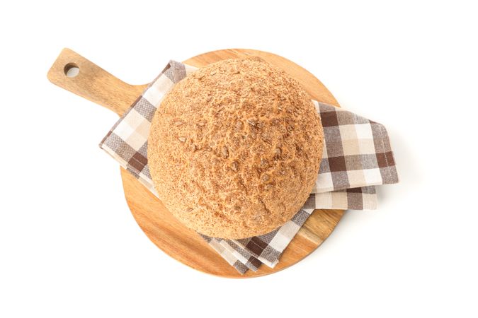 Wheat bread and kitchen towel on cutting board isolated on blank background, top view