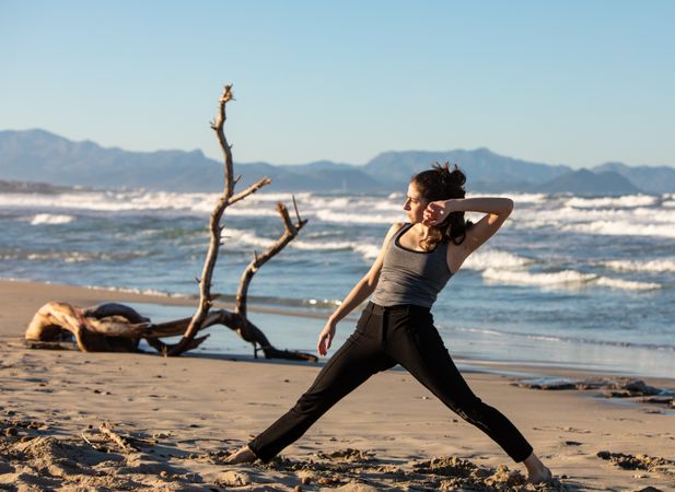 Young woman dancing and posing near water on shore