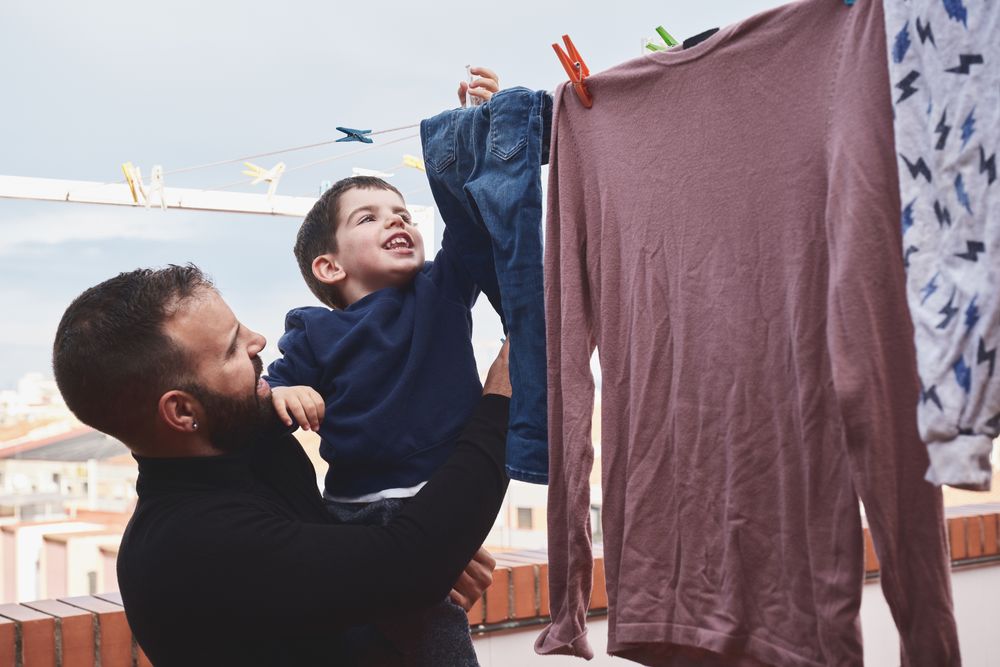 Father and son hanging clothes on rope