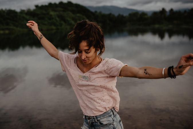 Cheerful woman dancing near lake