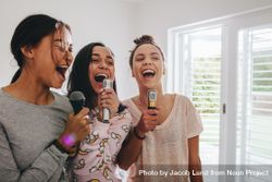 Group of young women singing holding microphones standing in bright bedroom 5qq315