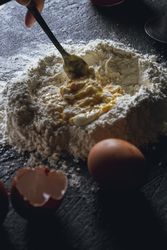 Cook preparing dough with egg and flour