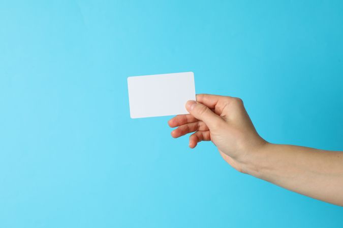 Female hand holding empty business card on blue background