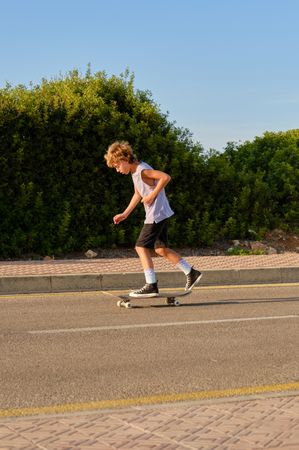 Boy riding skateboard along road
