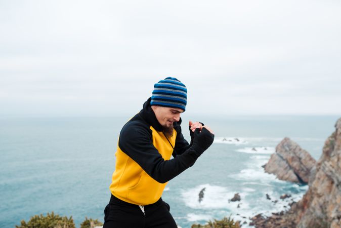 Kickboxer training on cliff near sea
