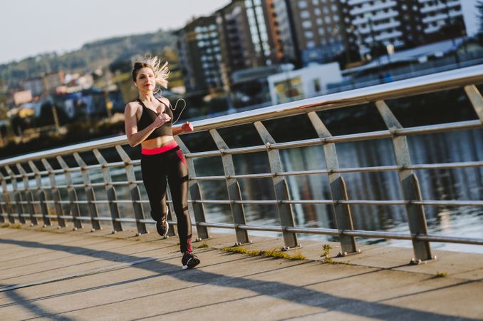 Woman running on embankment near water