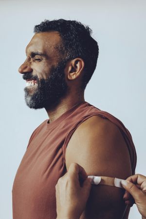 Smiling man having bandaid placed after vaccination