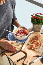 Unrecognizable woman having healthy breakfast on terrace