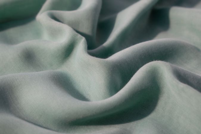 Nude green fabric wavy crumpled background texture with copy space.