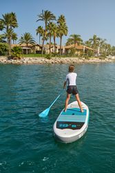 Boy on paddleboard near tropical resort on sunny day
