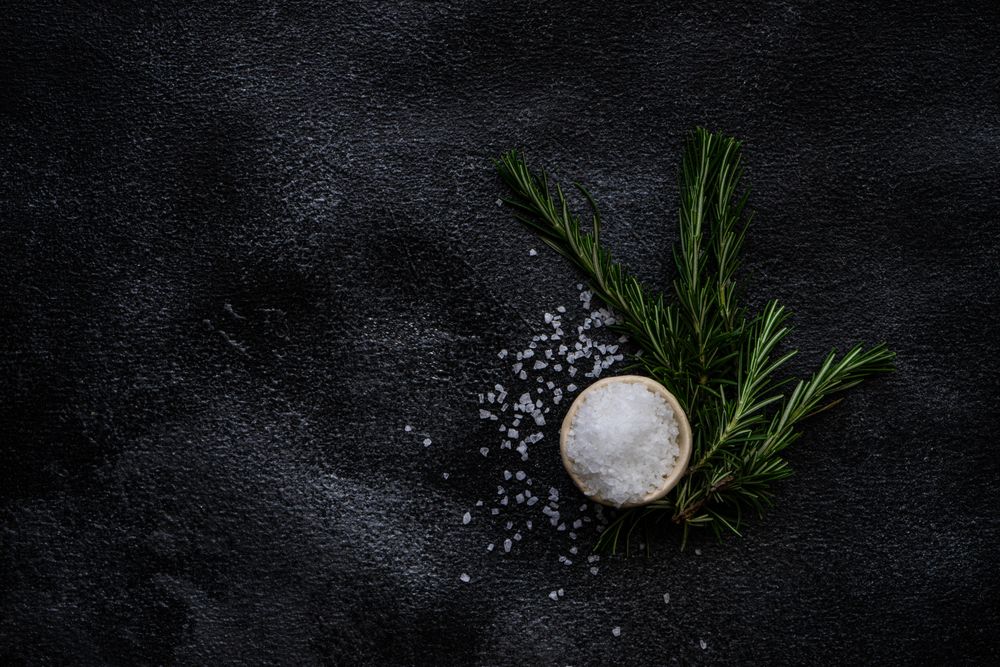 Top view of salt and rosemary on kitchen counter, vertical