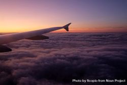 Window seat view of airplane wing over clouds during sunset 0gMrl4