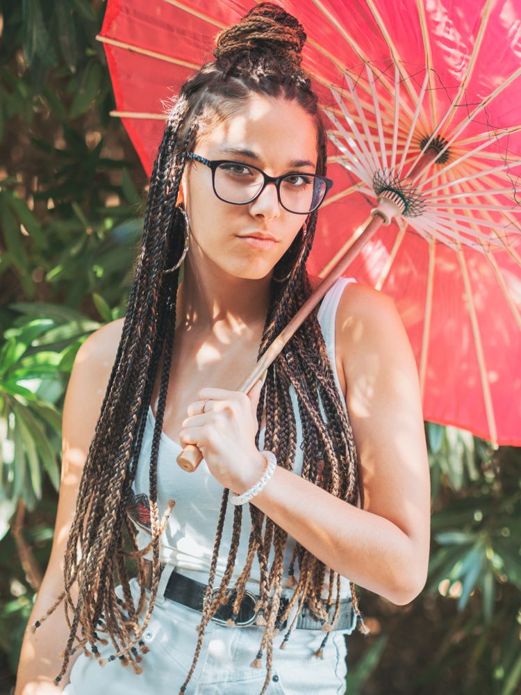 Fit young female with umbrella standing near blooming trees