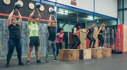 Athletes exercising with kettlebells and doing box jumps