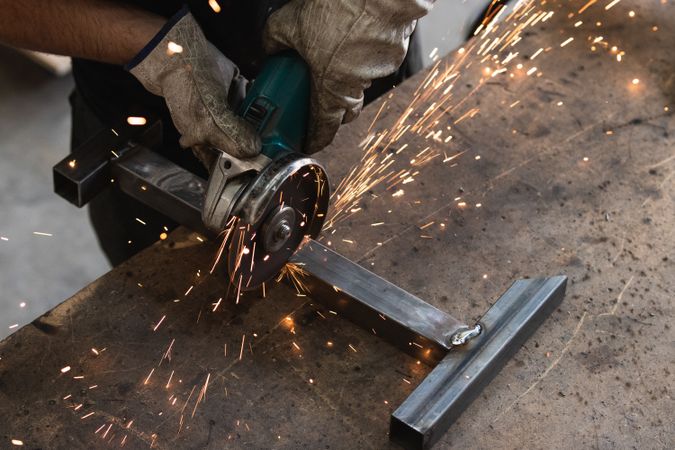Male worker using electric grinder in workshop