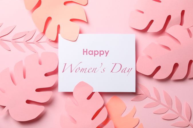 Decorative palm leaves and inscription Happy women's day on color background, top view