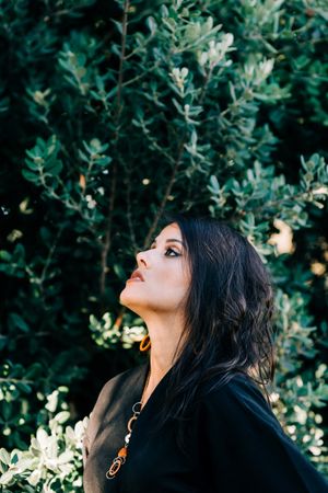 Smiling female looking out of green bushes