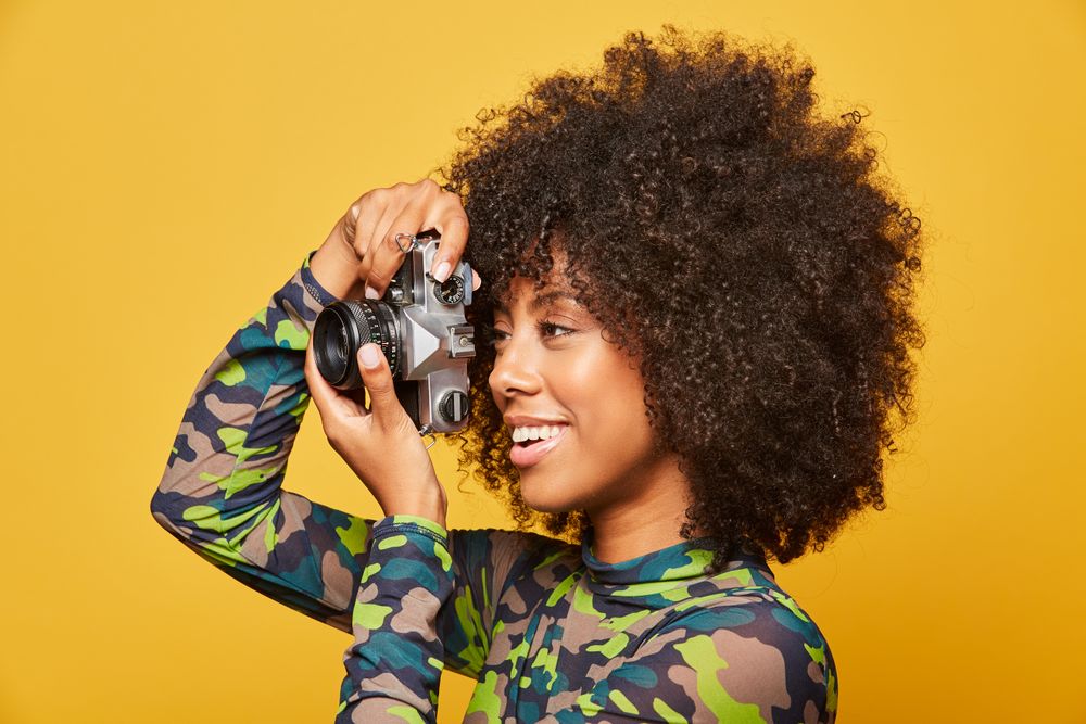 Trendy Black female paparazzi holding camera