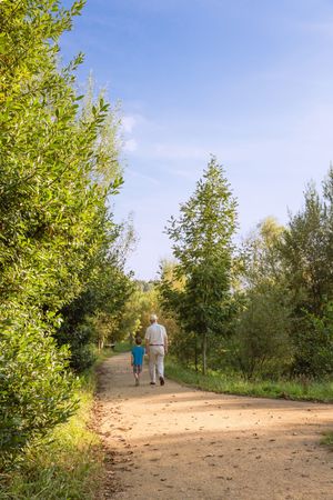 Grandfather and grandchild walking outdoors, vertical