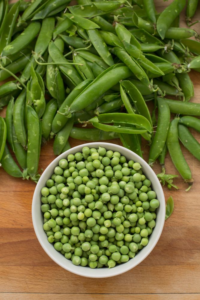 Fresh peas and pea pods on wooden background