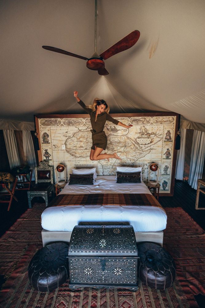 Woman jumping on bed in hotel room