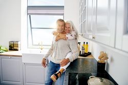 Happy mature couple in kitchen with woman sitting on counter
