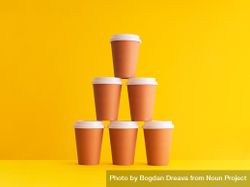 Pyramid of disposable coffee cups on yellow background 0KPlA5